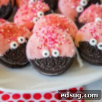 A charming white tray showcasing a collection of cheerful Love Bug Oreo Cookies, each featuring a bright red chocolate coating and cute candy eyes.