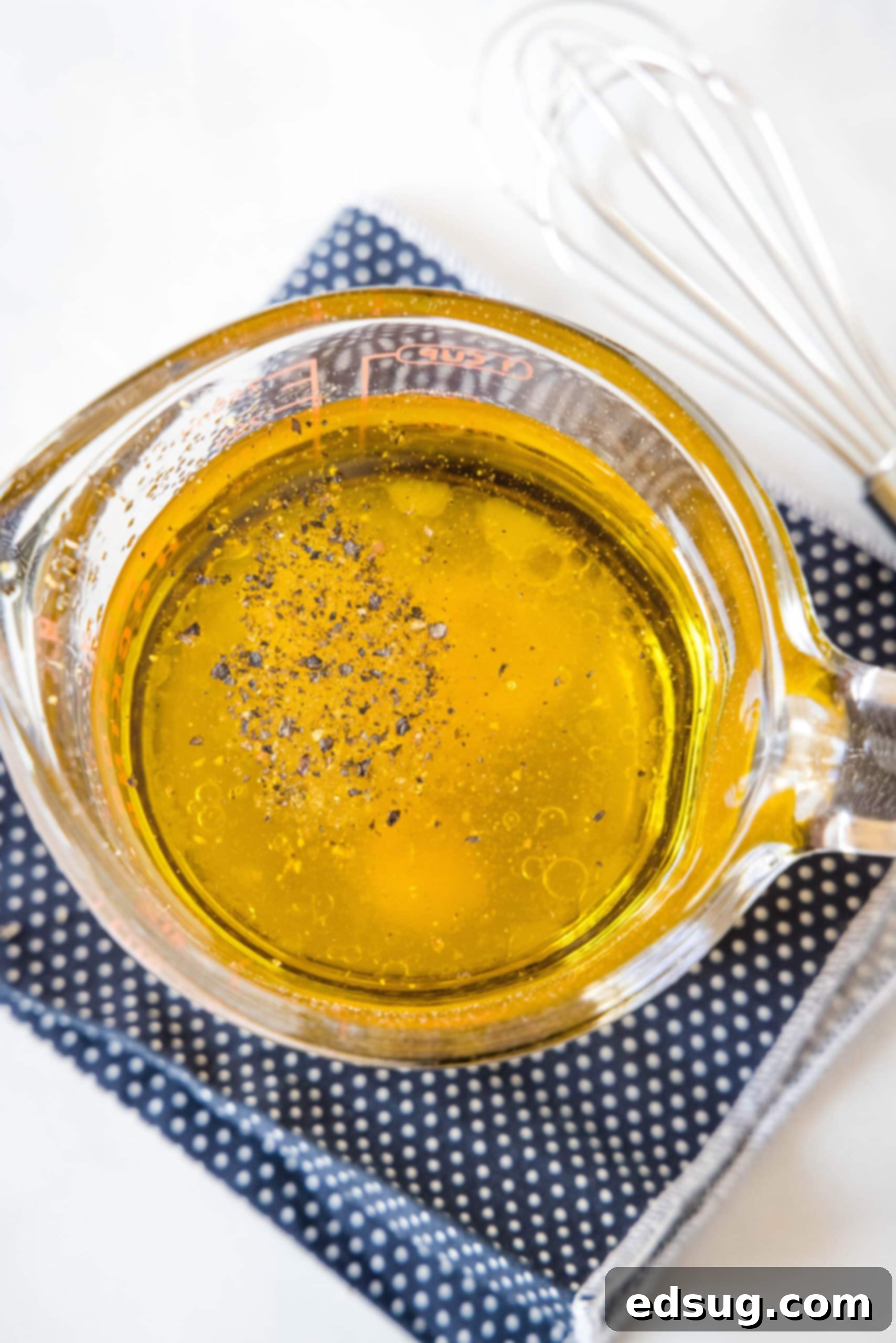Overhead view of the ingredients for apple cider vinaigrette combined in a measuring cup.
