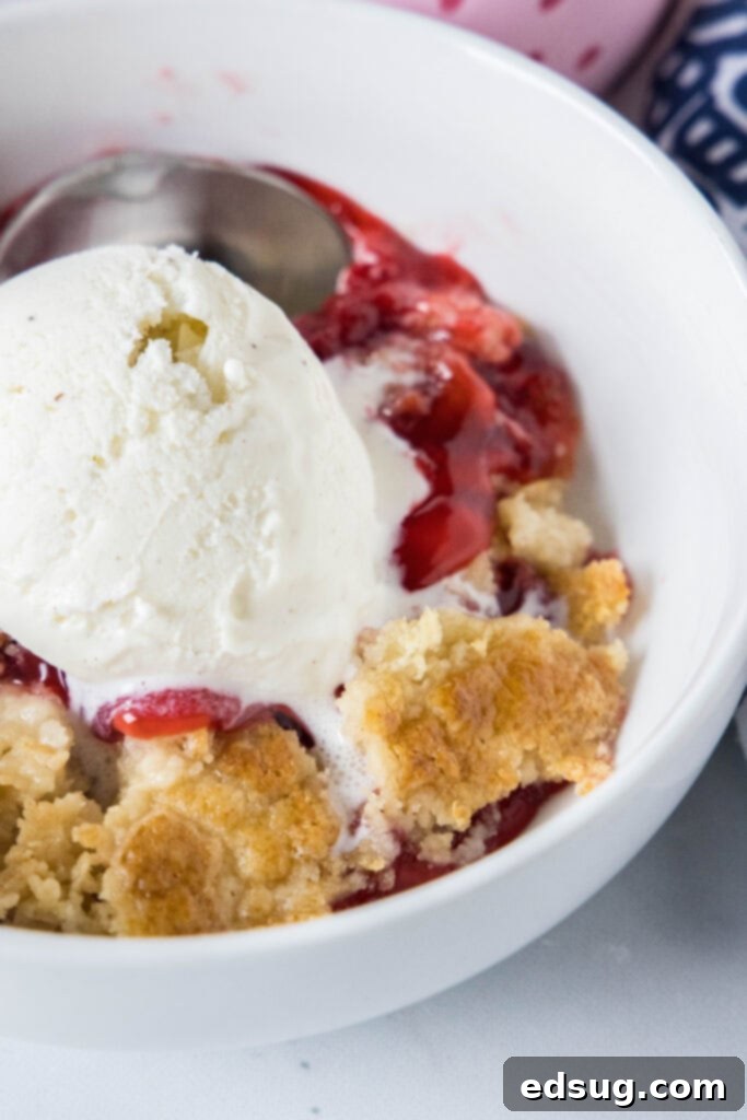 strawberry dump cake in a bowl topped with ice cream