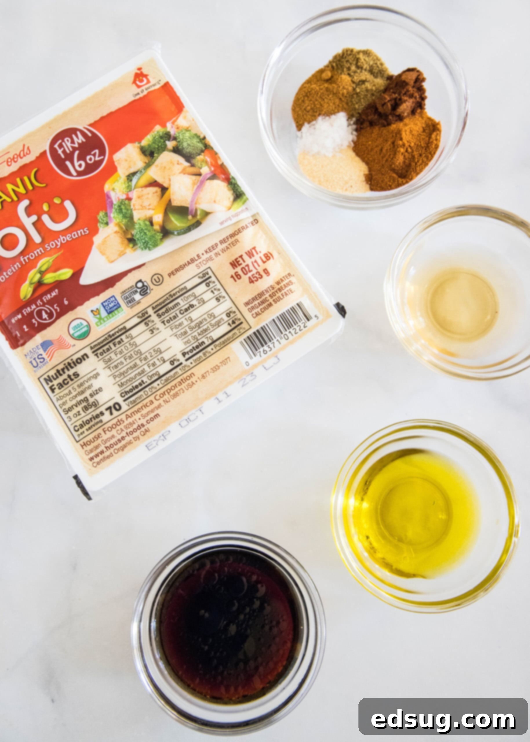 An overhead view of various fresh ingredients laid out for making the tofu taco filling, including tofu, spices, and sauces.