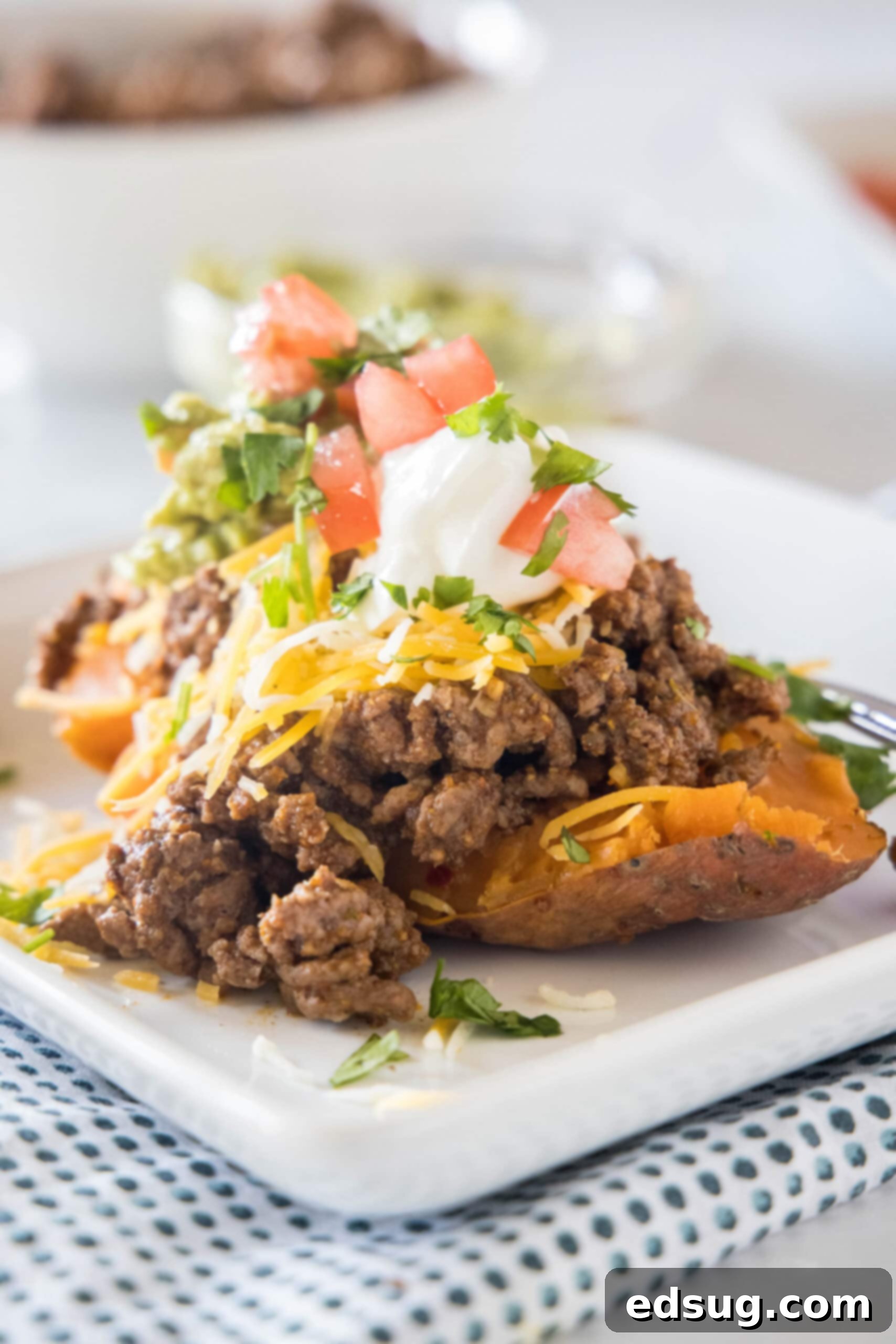 A taco sweet potato piled with taco toppings served on a white plate.