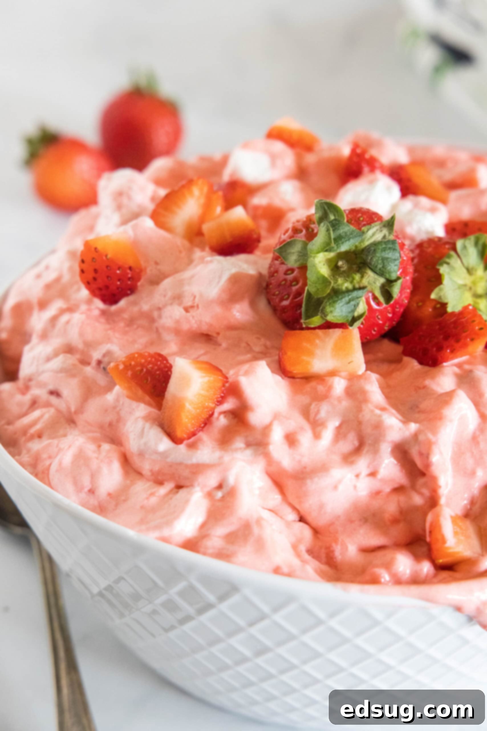 Strawberry fluff topped with chopped strawberries in a white bowl, ready to be served.