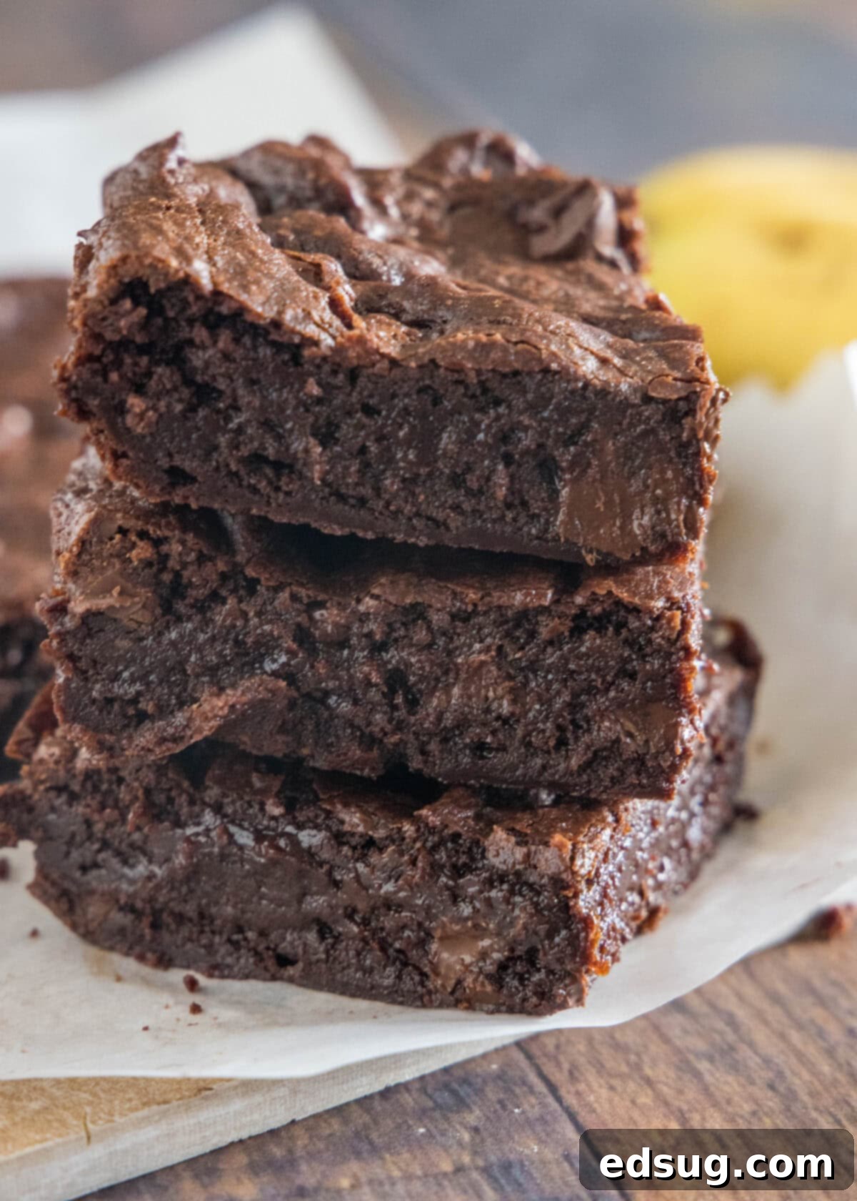 stack of fudgy banana brownies on cutting board with shiny crackly tops