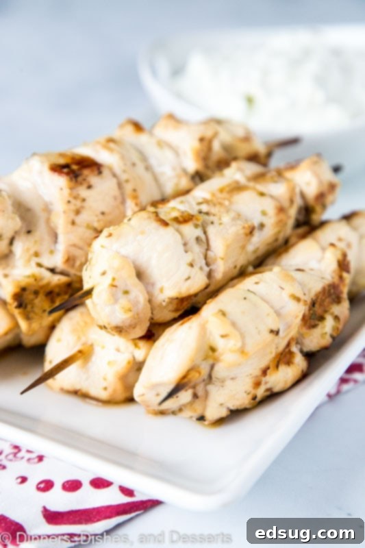 Chicken Souvlaki skewers on a white plate with homemade tzatziki sauce