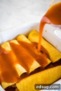 pouring enchilada sauce over rolled enchiladas