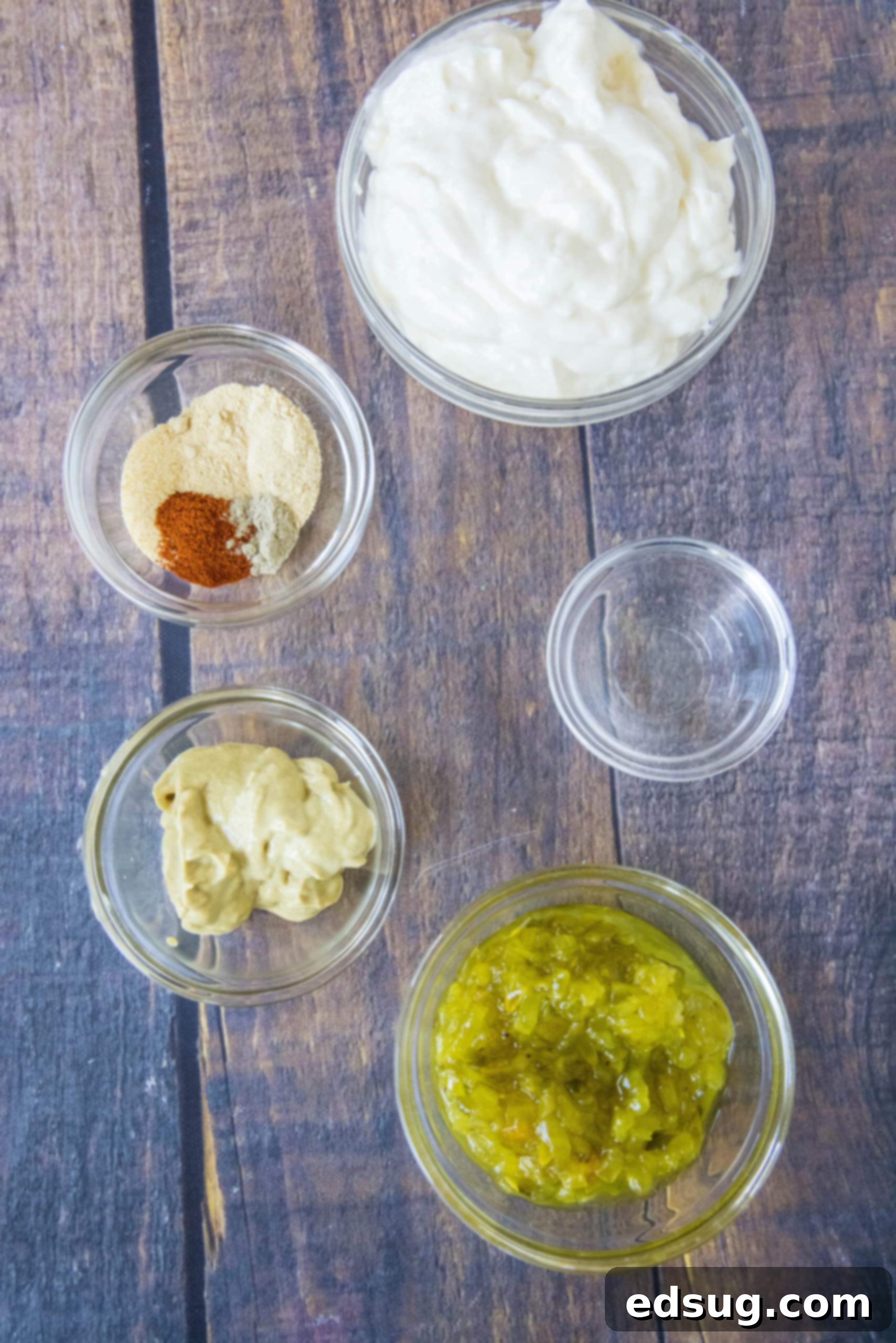 Various ingredients laid out on a clean counter, including mayonnaise, sweet pickle relish, Dijon mustard, white vinegar, and a selection of spices, ready for making homemade Big Mac Sauce.