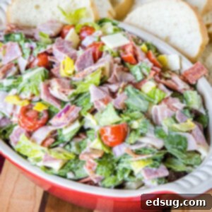 Hoagie dip in a red ceramic serving bowl with bread slices in the background.