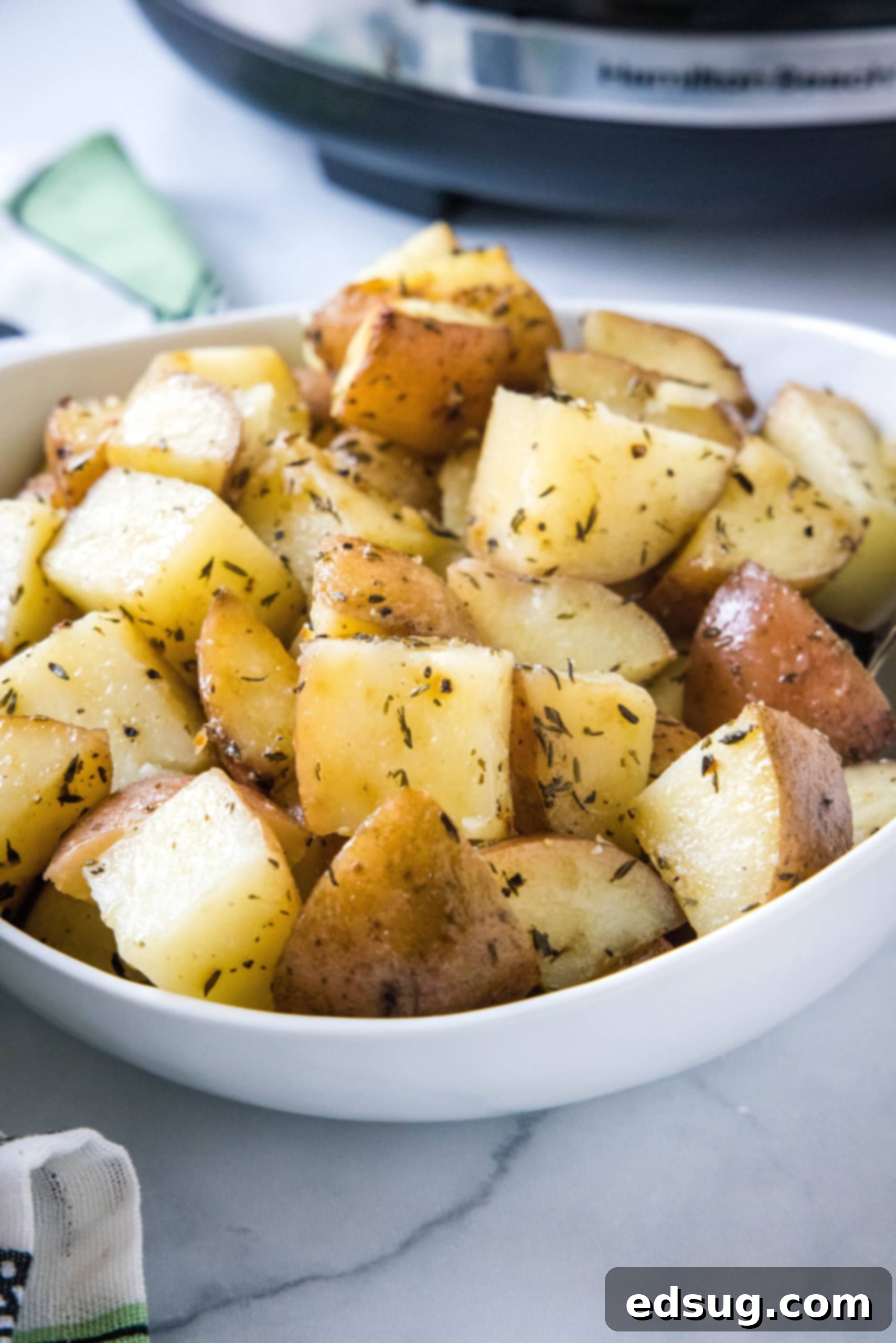 A bowl of perfectly cooked, seasoned slow cooker potatoes, garnished with fresh herbs.