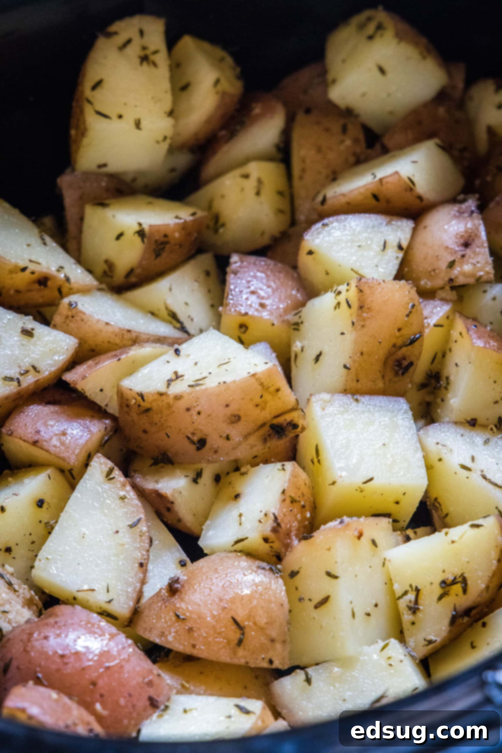 Close-up of golden, cooked seasoned potatoes inside the slow cooker, ready to serve.
