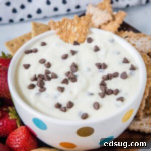 Creamy Cannoli dip in a decorative bowl, perfectly garnished with chocolate chips, on a rustic wooden platter.