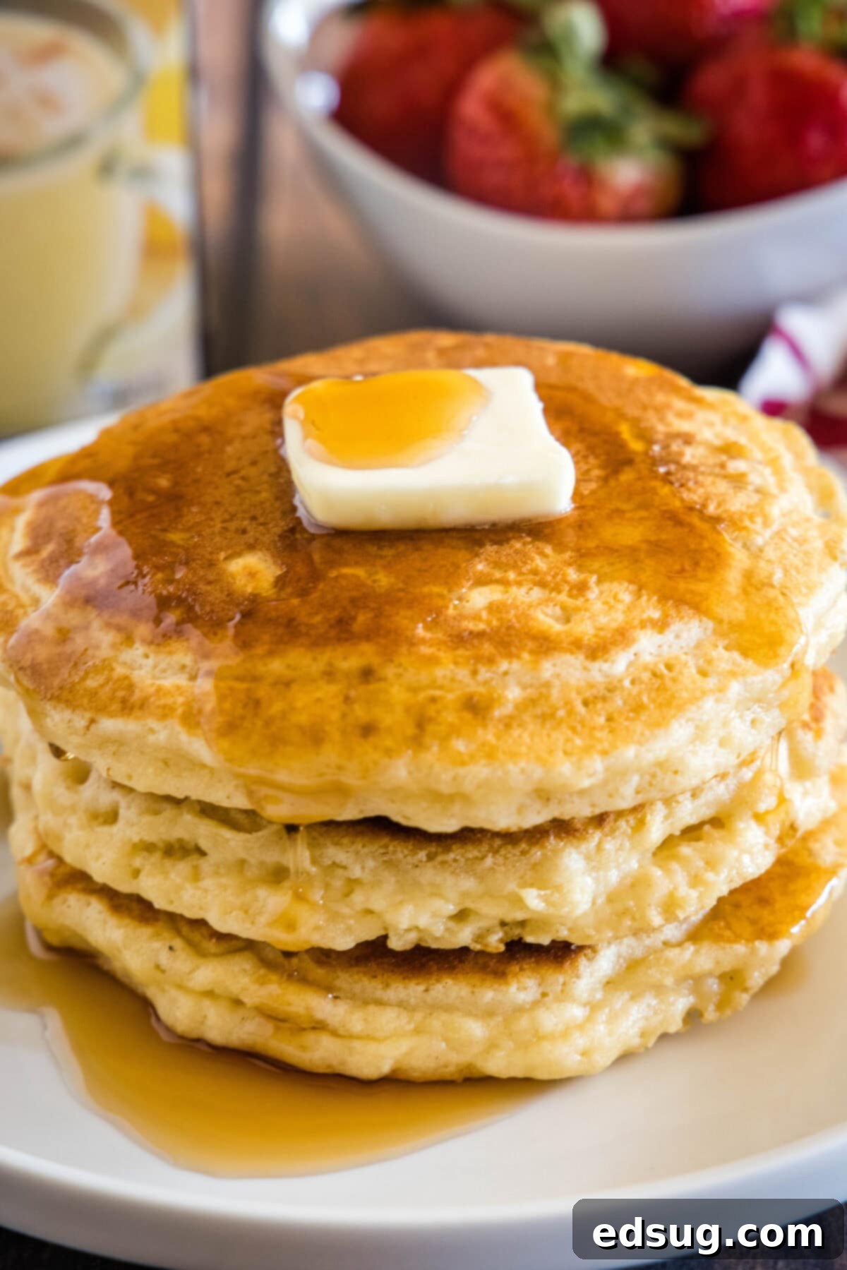 Festive Eggnog Pancakes 7 A final shot of fluffy eggnog pancakes drizzled with syrup on a plate, ready to be enjoyed.