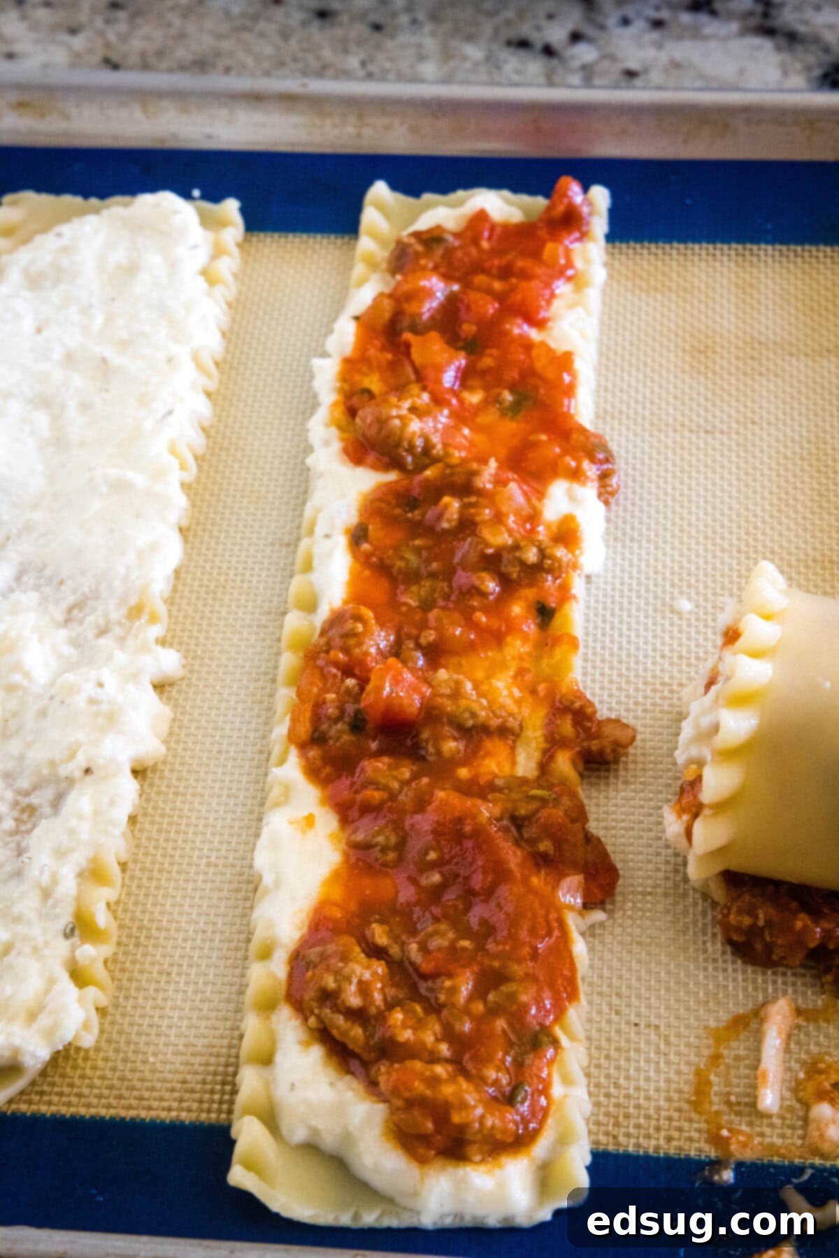 Sauce spread over a lasagna sheet on a baking pan.