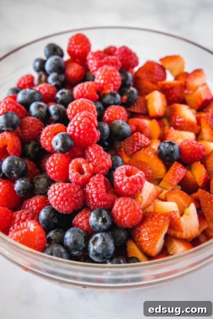 Berry Medley Jam 3 A vibrant bowl filled with fresh mixed berries including bright red strawberries, deep purple blueberries, and crimson raspberries.