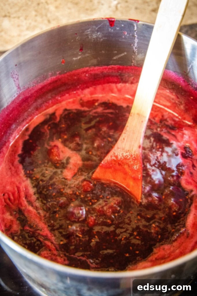 Berry Medley Jam 5 Mixed berry jam simmering in a large pot on the stove, bubbling gently as it thickens.