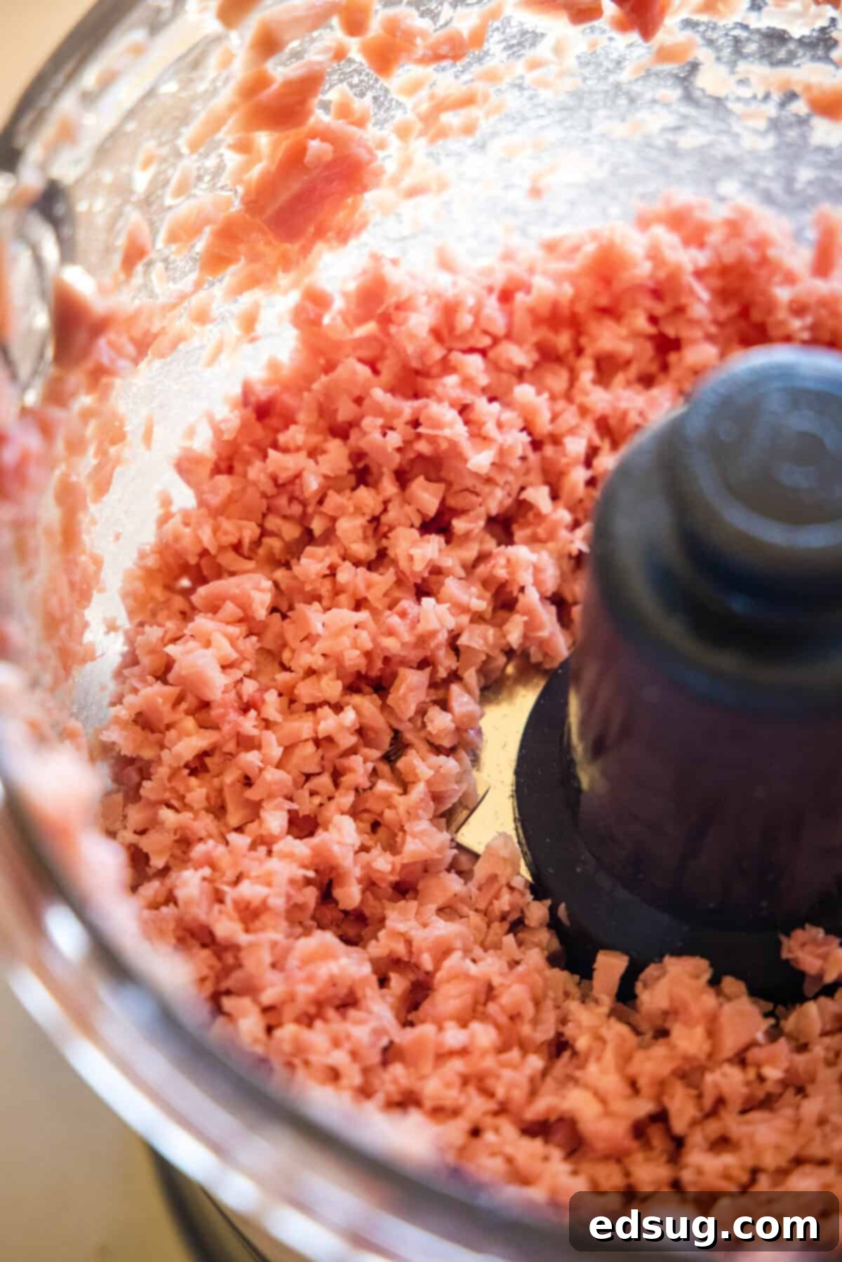 Finely minced ham and ground pork mixture in a food processor, ready to be shaped into ham balls.