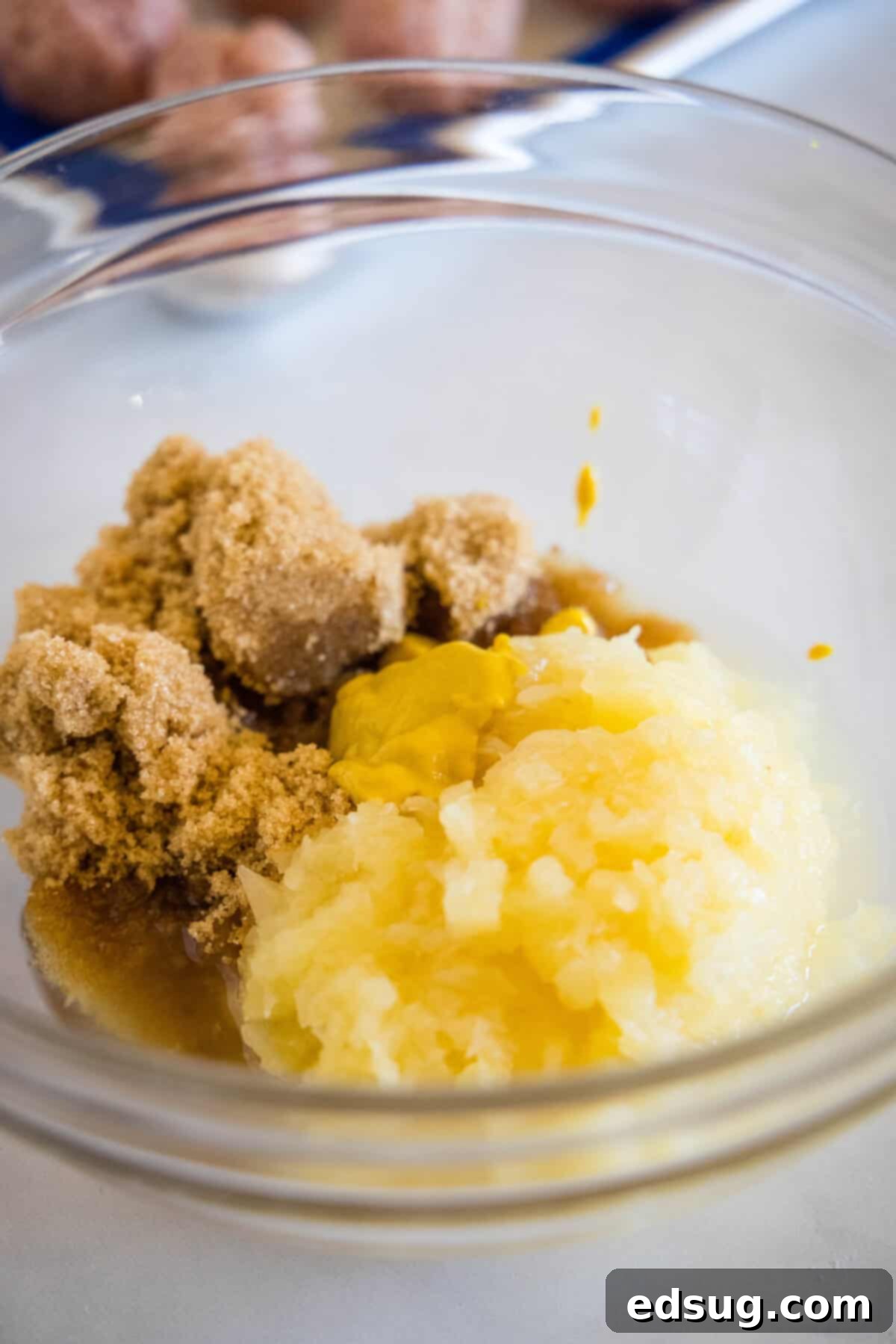 Brown sugar, crushed pineapple, cider vinegar, and yellow mustard mixed in a glass bowl to create the sweet ham ball sauce.