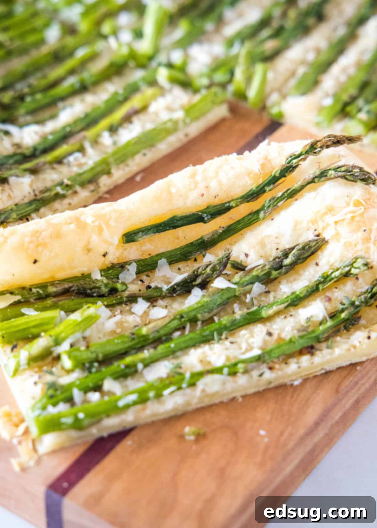 close up sliced asparagus tart on cutting board, showing golden crust and tender asparagus