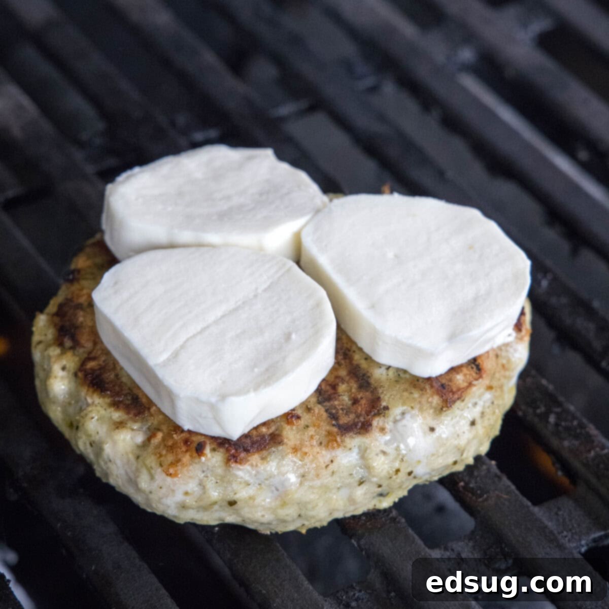 chicken burger topped with melting mozzarella cheese on the grill