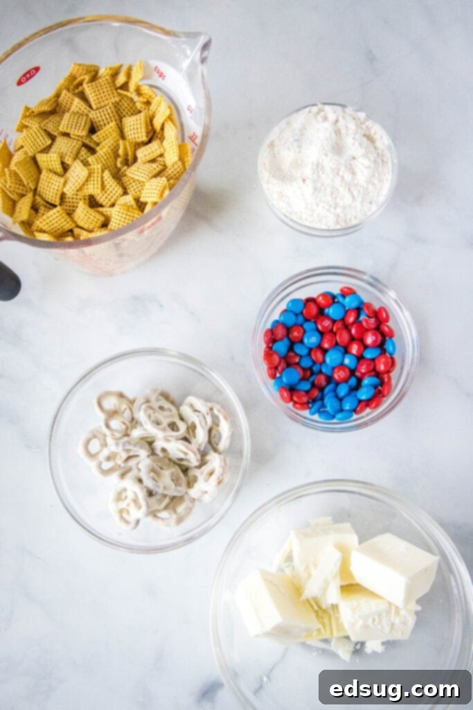 Key ingredients for Red, White & Blue Muddy Buddies including Chex cereal, white chocolate, cake mix, M&M's, pretzels, and sprinkles, laid out for preparation.
