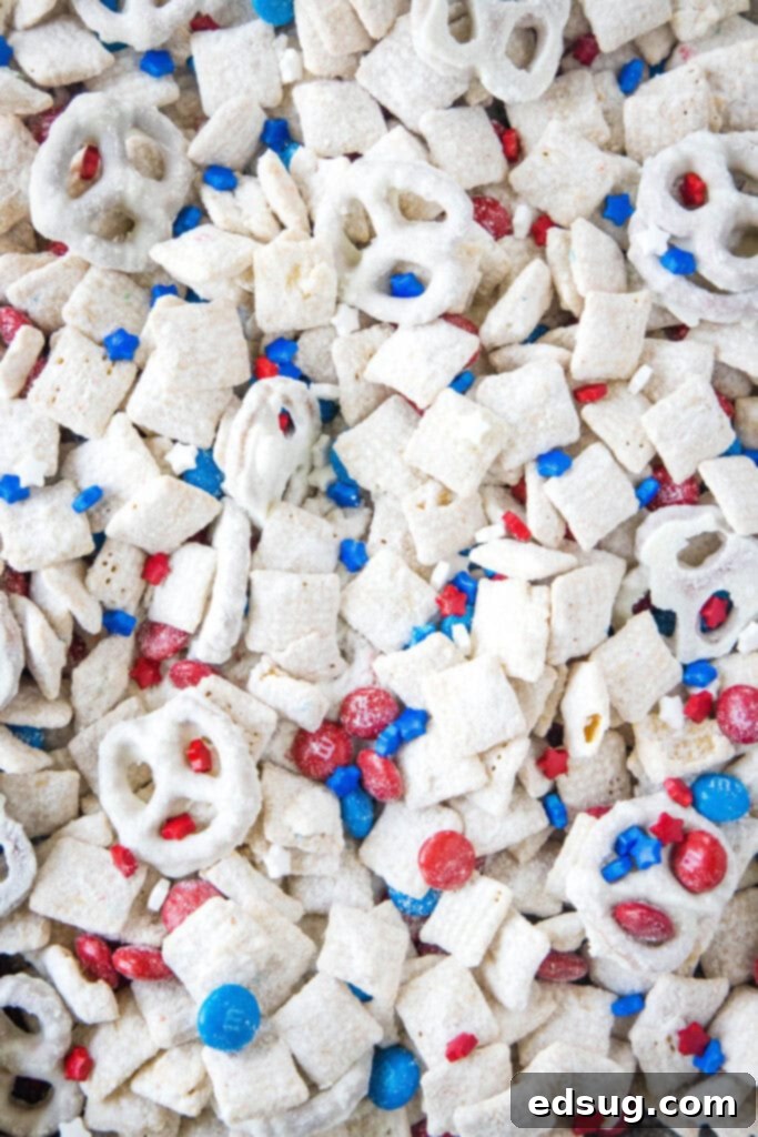 Finished Red, White & Blue Muddy Buddies snack mix scattered on a serving tray, adorned with M&M's, pretzels, and sprinkles, ready for a festive occasion.