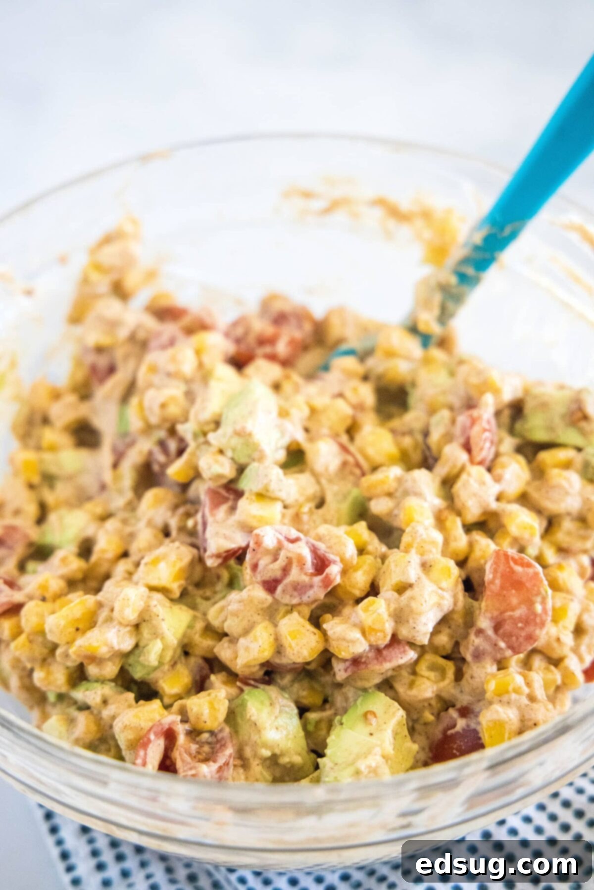 Corn salad in a mixing bowl with a spatula