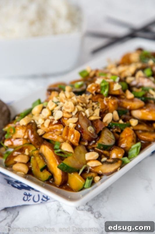 A vibrant plate of homemade Kung Pao Chicken stir-fry, garnished with chopped peanuts and green onions.