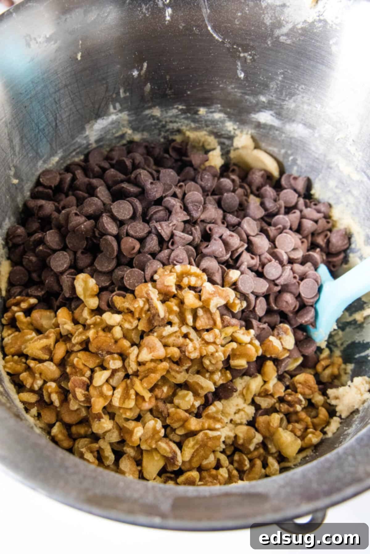 Congo bars are thick and gooey cookie bars loaded with two types of chocolate and crunchy walnuts. Make them in one bowl in minutes! Chocolate chips and walnuts being gently folded into the rich, golden cookie bar batter in a metal mixing bowl.