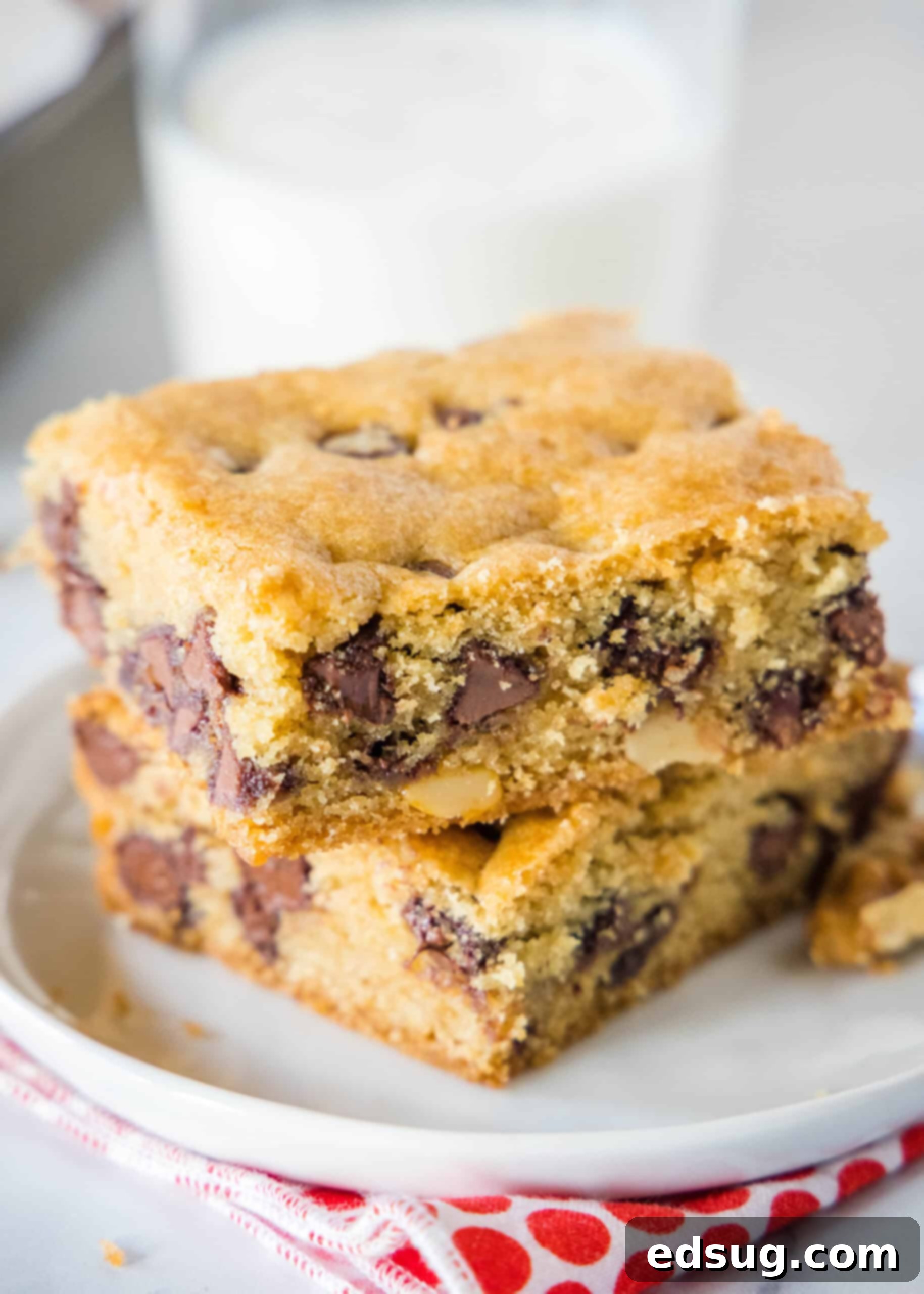 Congo bars are thick and gooey cookie bars loaded with two types of chocolate and crunchy walnuts. Make them in one bowl in minutes! Two perfectly baked, thick Congo bars, showcasing their rich texture and abundant chocolate, stacked on a clean white plate.