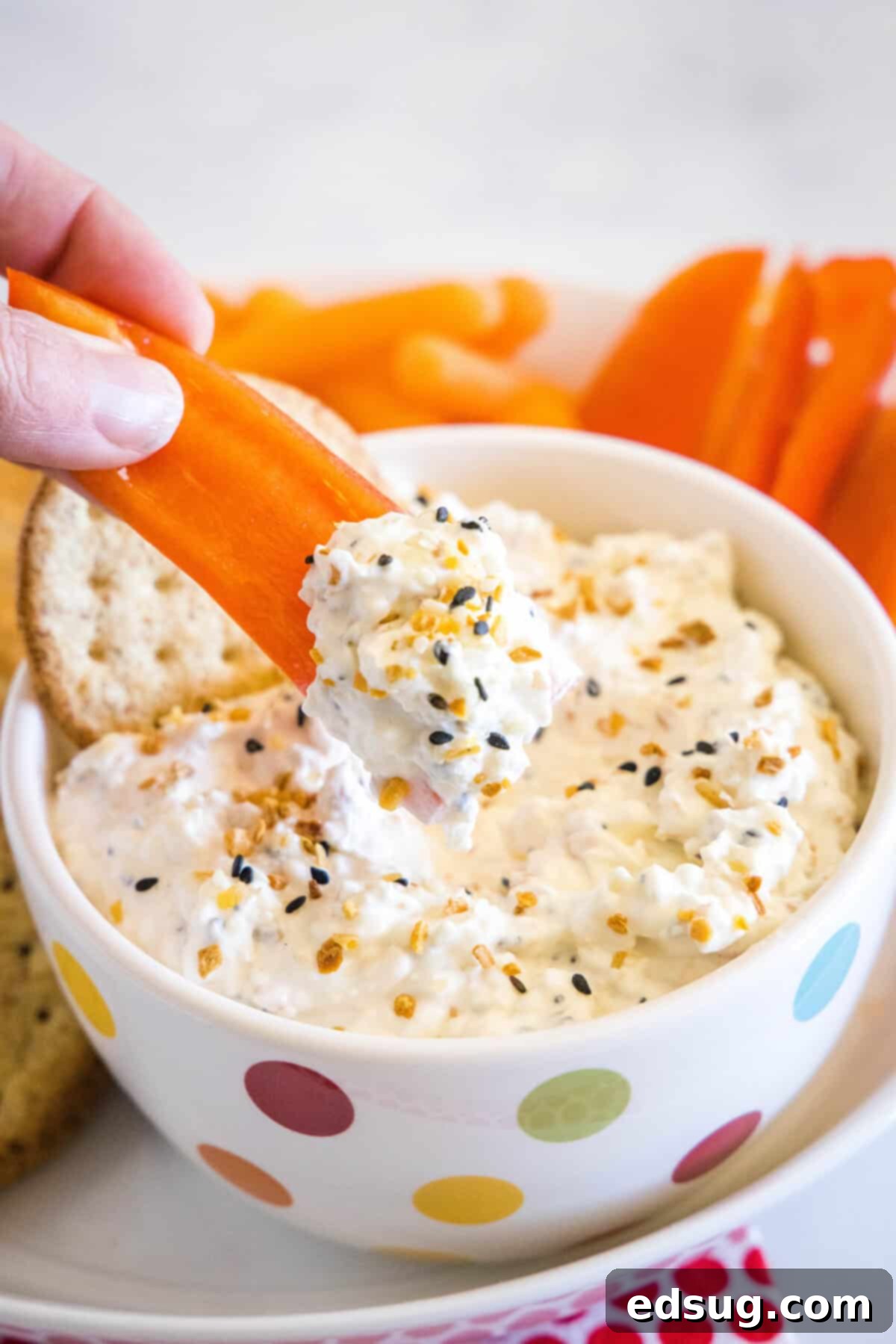 scooping everything bagel dip with a red pepper