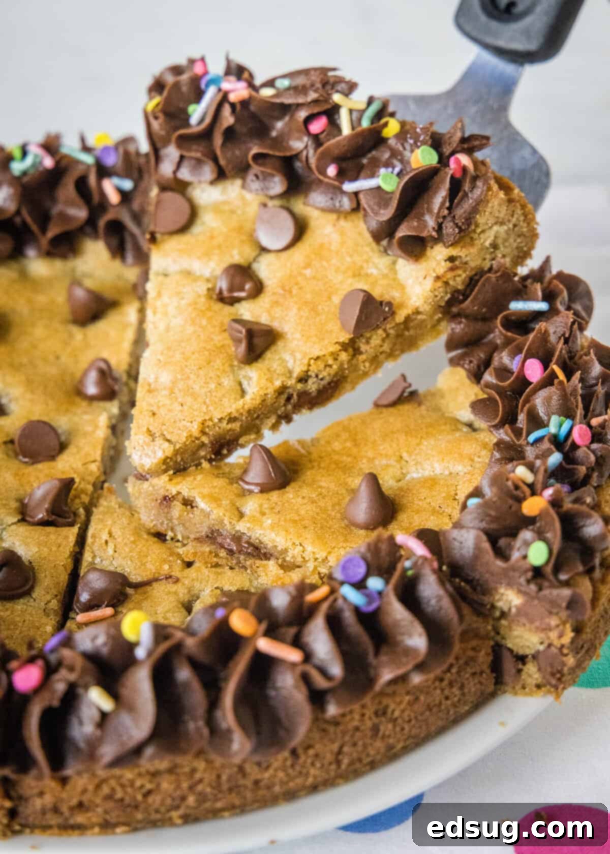A perfect slice of homemade chocolate chip cookie cake on a spatula, ready to be served for a birthday or party.