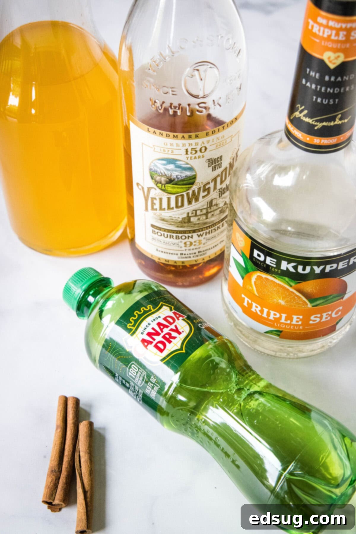 Ingredients for Bourbon Apple Cider Cocktail including apple cider, bourbon, ginger ale, and cinnamon sticks