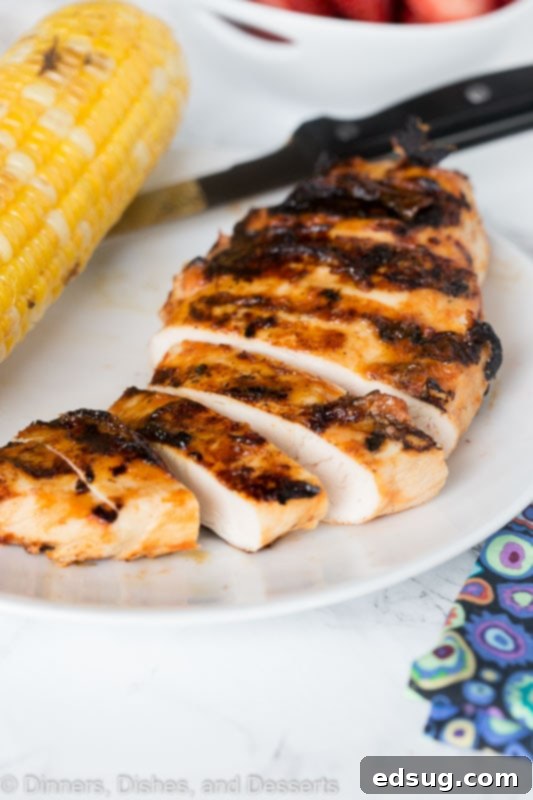 sliced barbecue chicken on a plate next to corn on the cob