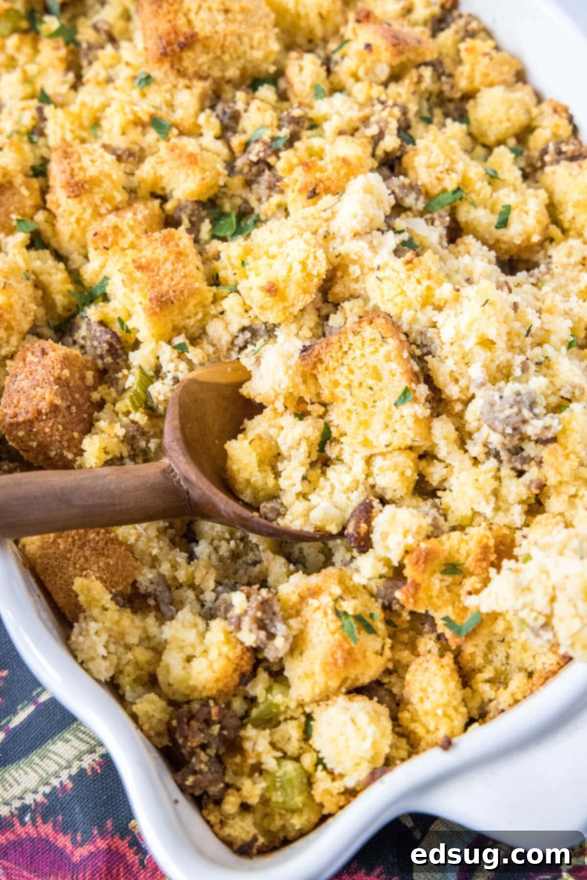 A wooden spoon in a casserole dish full of cornbread stuffing