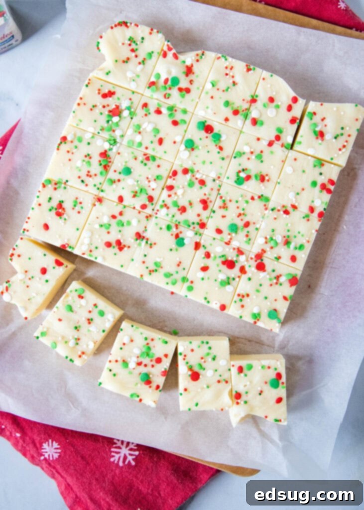 Frosted Sugar Cookie Fudge 6 Beautifully sliced sugar cookie fudge squares arranged on a wooden board, showcasing their vibrant sprinkles and creamy texture.