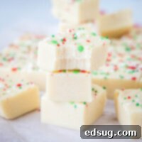 Frosted Sugar Cookie Fudge 7 Stacked sugar cookie fudge squares, one with a bite taken out, showcasing the creamy texture and colorful sprinkles.