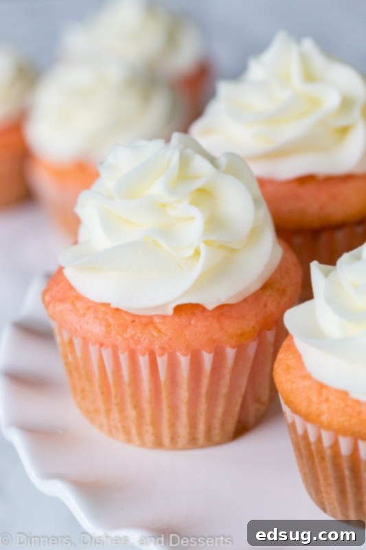 strawberry almond cupcakes topped with frosting on a cake stand