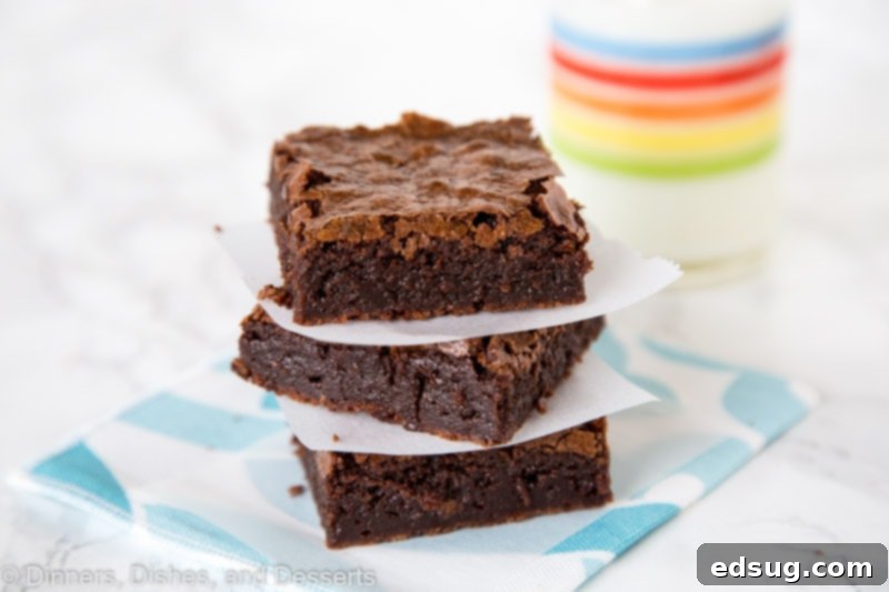 brownies stacked next to a glass of milk