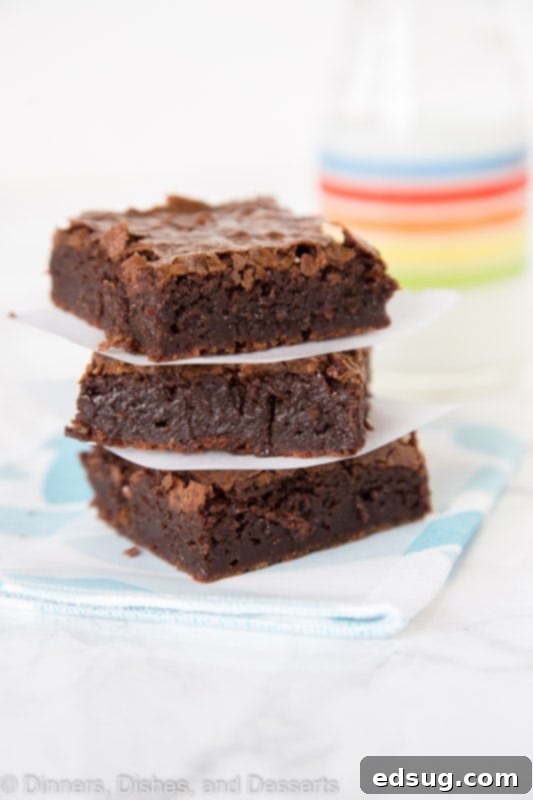 brownies stacked next to a glass of milk