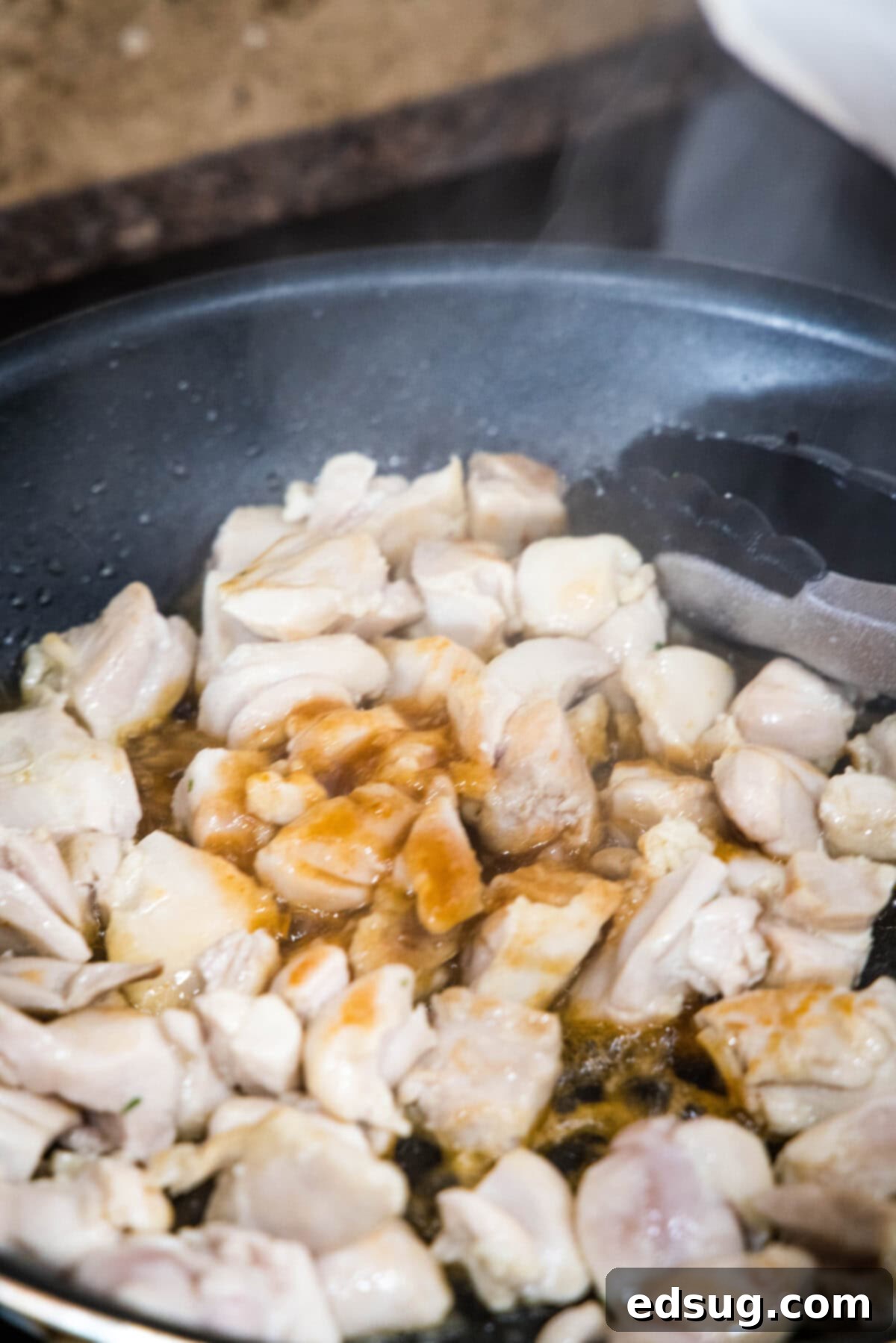 adding honey sriracha sauce to skillet with chicken