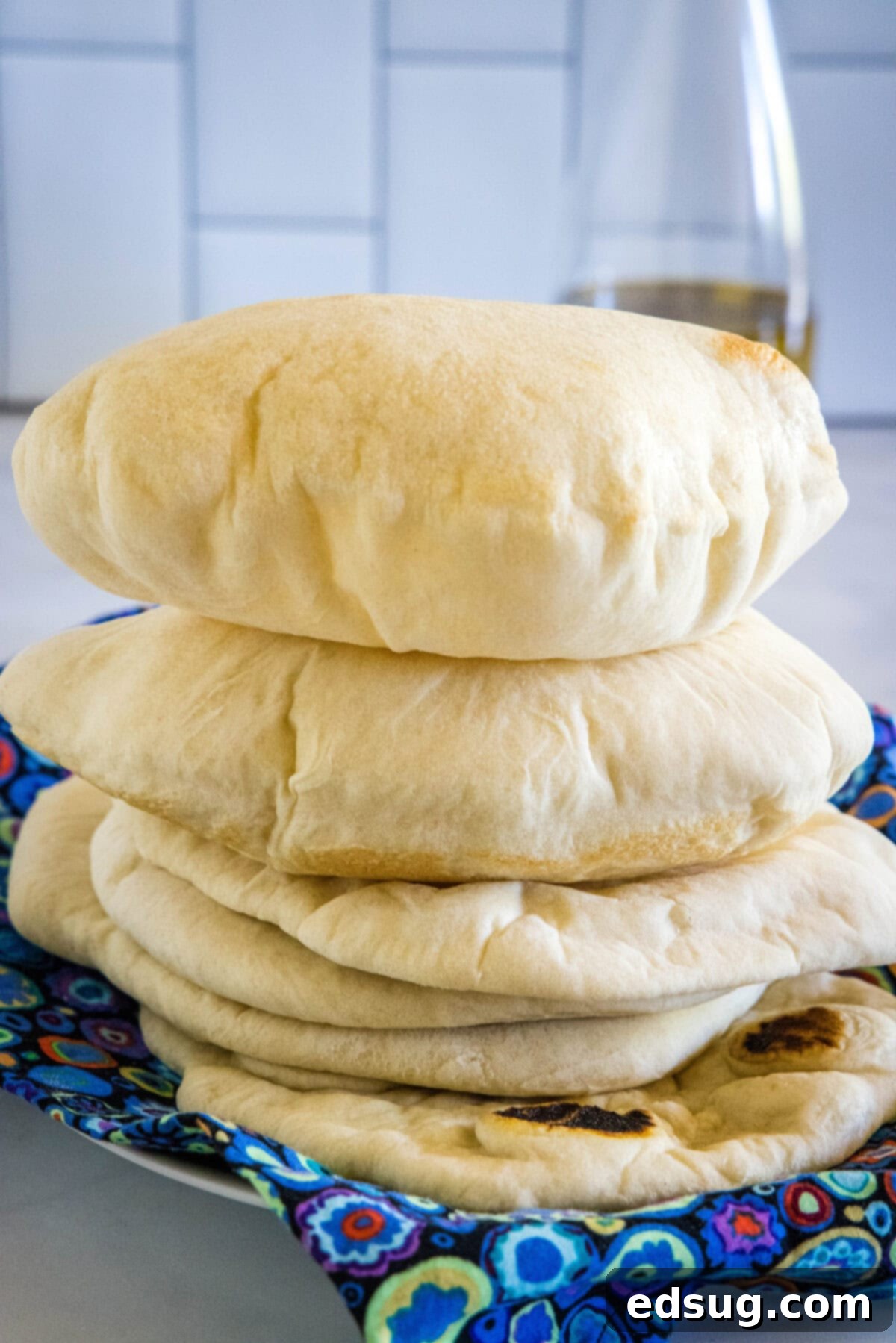 Crafting Perfect Pita 2 Freshly baked fluffy homemade pita breads stacked neatly on a blue fabric, ready to be served.