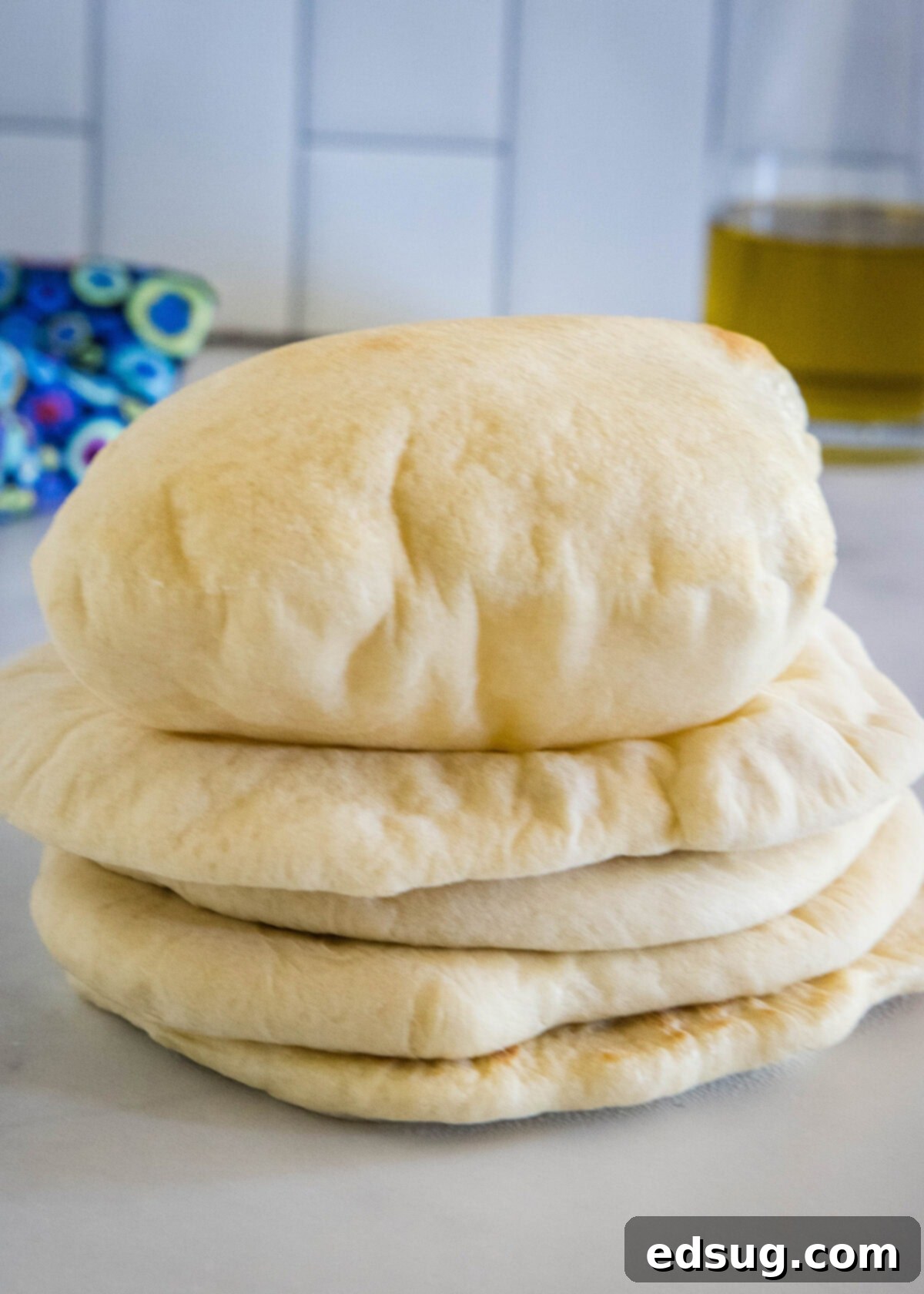 Crafting Perfect Pita 12 A stack of warm, fluffy homemade pita breads resting on a kitchen countertop, showcasing their soft texture.