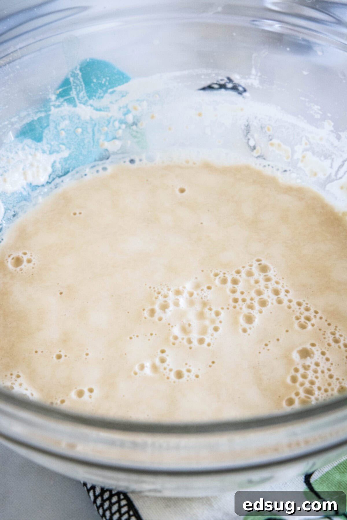 Crafting Perfect Pita 4 A mixture of warm water, yeast, sugar, and a portion of flour in a glass bowl, activating the yeast.