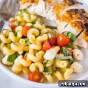 cropped in close up of pasta salad next to a piece of chicken