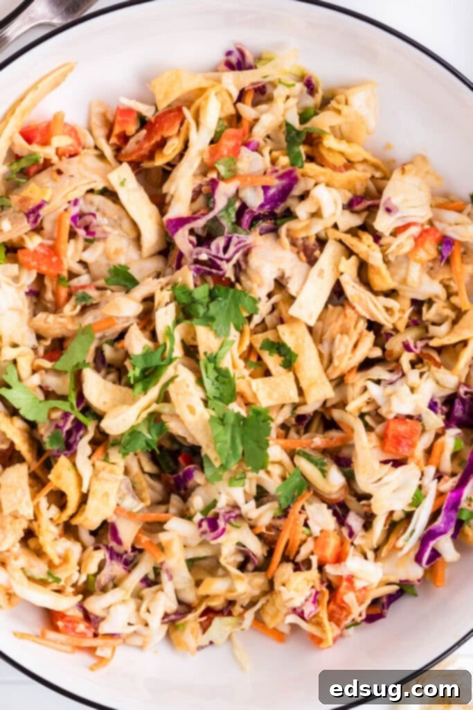 a serving bowl with vibrant Thai chicken salad, showcasing fresh ingredients and a rich peanut dressing