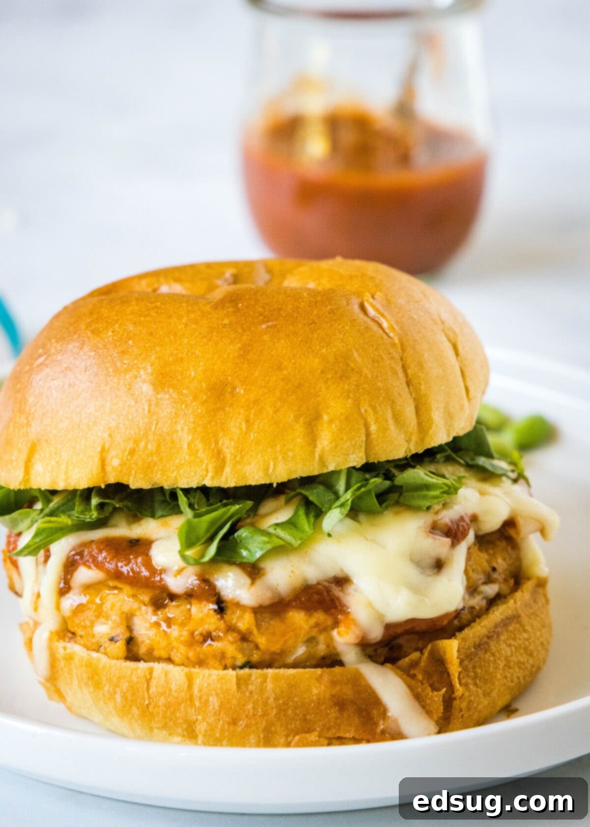 Chicken Parm Burgers 2 Two juicy Chicken Parmesan Burgers on a white plate, topped with melted mozzarella and fresh basil, ready to be served.