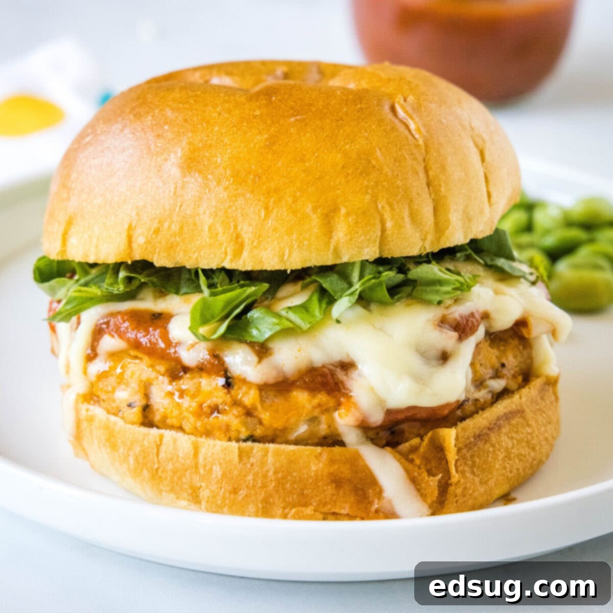 Chicken Parm Burgers 8 Close-up view of a beautifully presented Chicken Parmesan Burger, highlighting the melted cheese, basil, and toasted bun.