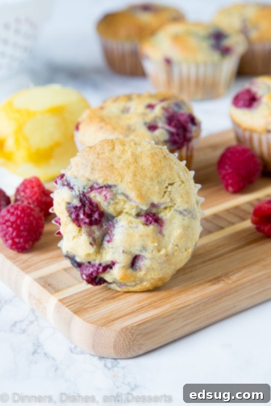 A perfectly baked lemon raspberry muffin with a delicate golden top, resting on a rustic wooden board, ready to be enjoyed.