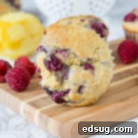A freshly baked lemon raspberry muffin, golden brown and speckled with berries, presented beautifully on a wooden surface.