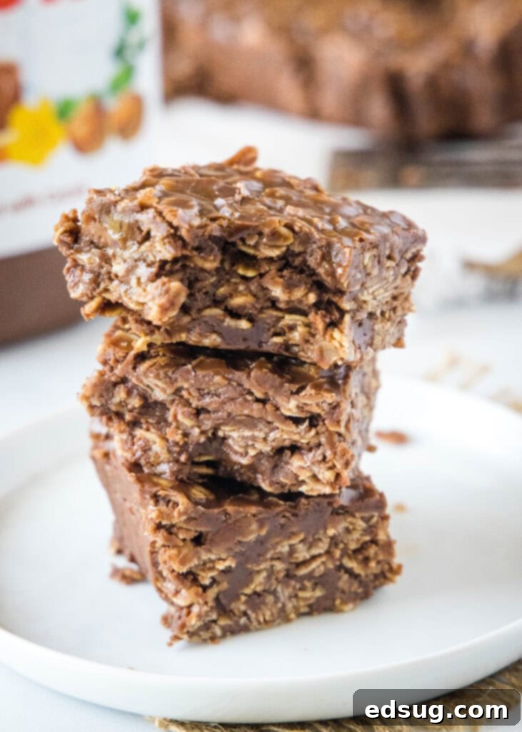 Dreamy No-Bake Nutella Bars 2 Stacked Nutella bars on a white plate with a bite taken out of the top bar, showcasing their soft, chewy texture.