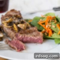 The Ultimate Grilled Ribeye 2 grilled steak on a plate with fresh rosemary and a side of vegetables